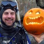 Darren Jaeckel smiles near a jack-o-lantern he carved underwater at the sixth annual Spooktacular Dive and Underwater Pumpkin Carving event Saturday, Oct. 26, 2019. (Ben Hohenstatt | Juneau Empire)