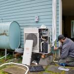 Jake Eames, right, and David Nash install an air-to-air heat pump system to a Mendenhall Valley home Thursday that formerly was using oil for heating in 2015. (Michael Penn | Juneau Empire)