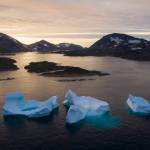 In this Aug. 16 photo, large icebergs float away as the sun rises near Kulusuk, Greenland. Rising temperatures and diminished snow and ice cover in the Arctic are imperiling ecosystems, fisheries and local cultures, according to a report issued Tuesday, Dec. 10 by the National Oceanic and Atmospheric Administration. (AP Photo/Felipe Dana, File)