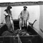 Paul Chukan of Naknek and Alec Alvarez stand in a sailboat in Bristol Bay. Courtesy Photo | Alaska State Digital Archives)