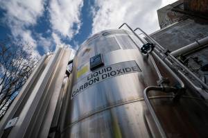 A liquid carbon dioxide containment unit stands outside the fabrication building of Glenwood Mason Supply Company, April 18, 2023, in the Brooklyn borough of New York. The Biden administration announced on Wednesday, May 17, $251 million for carbon capture and storage projects in seven states. (AP Photo / John Minchillo)