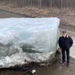 Eagle resident Steve Hamilton stands next to a block of Yukon River ice that the river lifted onto the 5-mile road between the town of Eagle and Eagle Village during an early river surge on May 12, 2023. (Courtesy Photo / Ned Rozell)