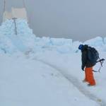 Craig George looks at polar bear tracks near an observing perch he and other biologists built on sea ice north of Utqiagvik in May 2010. The canvas on top is wrapped around two-by-fours to break the wind. (Photo by Ned Rozell)