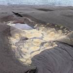 A sulfide scum filled hole is left behind on the Sheep Creek Delta after hydro dredging. (Jasz Garrett / Juneau Empire)