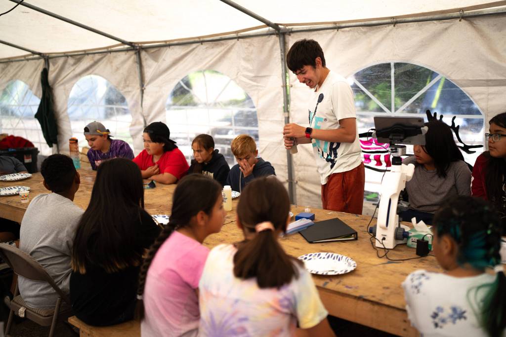Shawn Merry shows youths during a Sustainable Southeast Partnership culture camp how to use a microscope. He has worked with many community driven programs catalyzed through SSP including the Alaska Youth Stewards Program, KeexKwaan Community Forest Partnership, and now is working full time with the Organized Village of Kake. (Photo by Bethany Goodrich)
