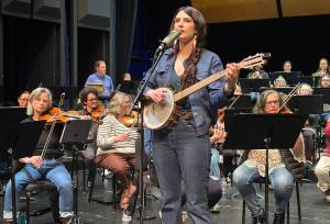 Juneau singer/songwriter Annie Bartholomew rehearses with the Juneau Symphony on Thursday, May 29, 2025, in the Juneau-Douglas High School: Yadaa.at Kalé auditorium. Two folk songs by Bartholomew about women during Klondike Gold Rush will be featured in rearrangements for orchestra during performances Saturday and Sunday. (Mark Sabbatini / Juneau Empire)