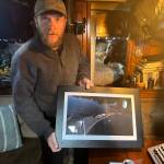 Blake Byers shows a photo of one of his beach art projects aboard his boat in Juneau on Tuesday, June 3, 2025. (Mark Sabbatini / Juneau Empire)