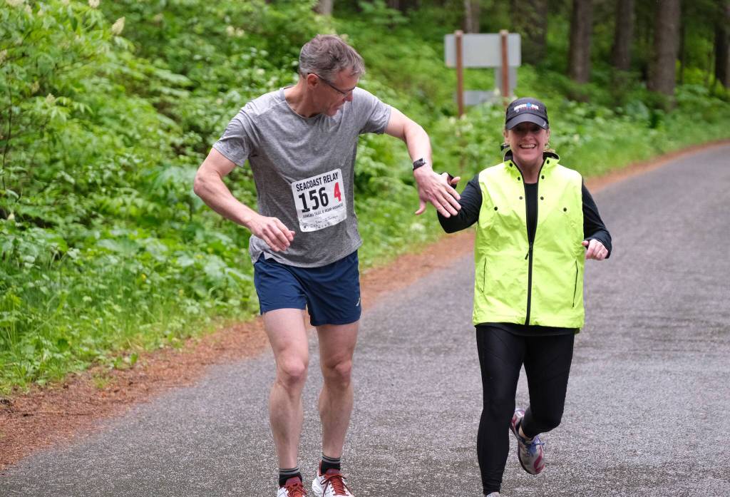 Team JACKDs Dan Robinson takes the hand off from Kim Campbell at Lena Beach Picnic Area during the Seacoast Relay on Sunday, June 8, 2025. (Klas Stolpe / Juneau Empire)