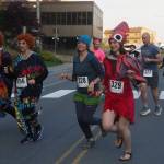 Runners cross Willoughby Avenue on Friday, June 20, 2025. Leading the pack are Adeline Souza and Heather Jones dressed as Mrs. Roper from the 1970s sitcom Threes Company. They were inspired by the nationwide phenomenon Mrs. Roper Romps. (Natalie Buttner / Juneau Empire)