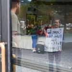 Laura Statts protests outside Centennial Hall on Saturday, hoping Rep. Nick Begich III, R-Alaska, will see her through the window. (Jasz Garrett / Juneau Empire)
