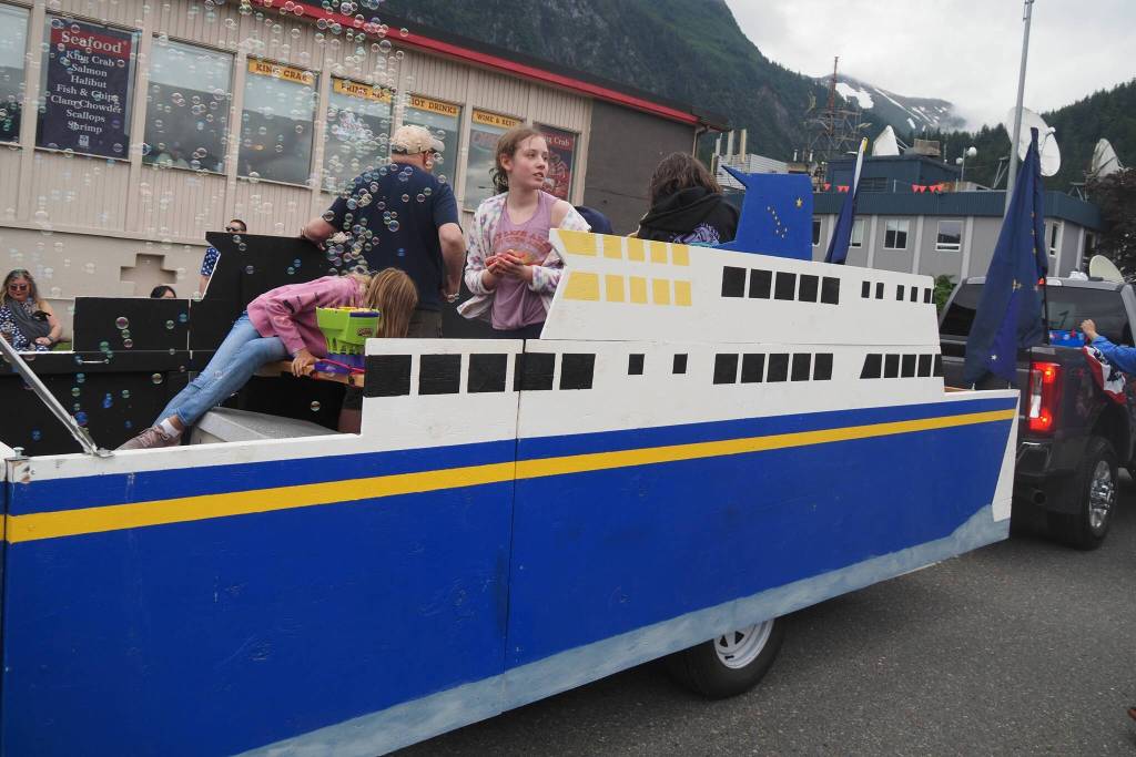 Kids throw candy from the Alaska Marine Highway Crew float, a part of the Juneau Central Labour Council submission. (Natalie Buttner / Juneau Empire)