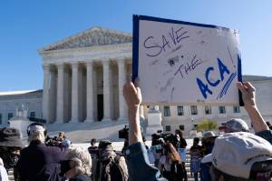 A demonstrator holds a sign in front of the U.S. Supreme Court as arguments are heard about the Affordable Care Act, Tuesday, Nov. 10, 2020, in Washington. (AP Photo / Alex Brandon)