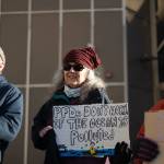 Larri Spengler holds a sign reading PFDs dont work if the ocean is polluted during an anti-LNG pipeline protest led by the Juneau-Douglas High School: Yadaa.at Kalé chapter of Alaska Youth for Environmental Action outside the Alaska State Capitol on Saturday, Jan. 24, 2026.